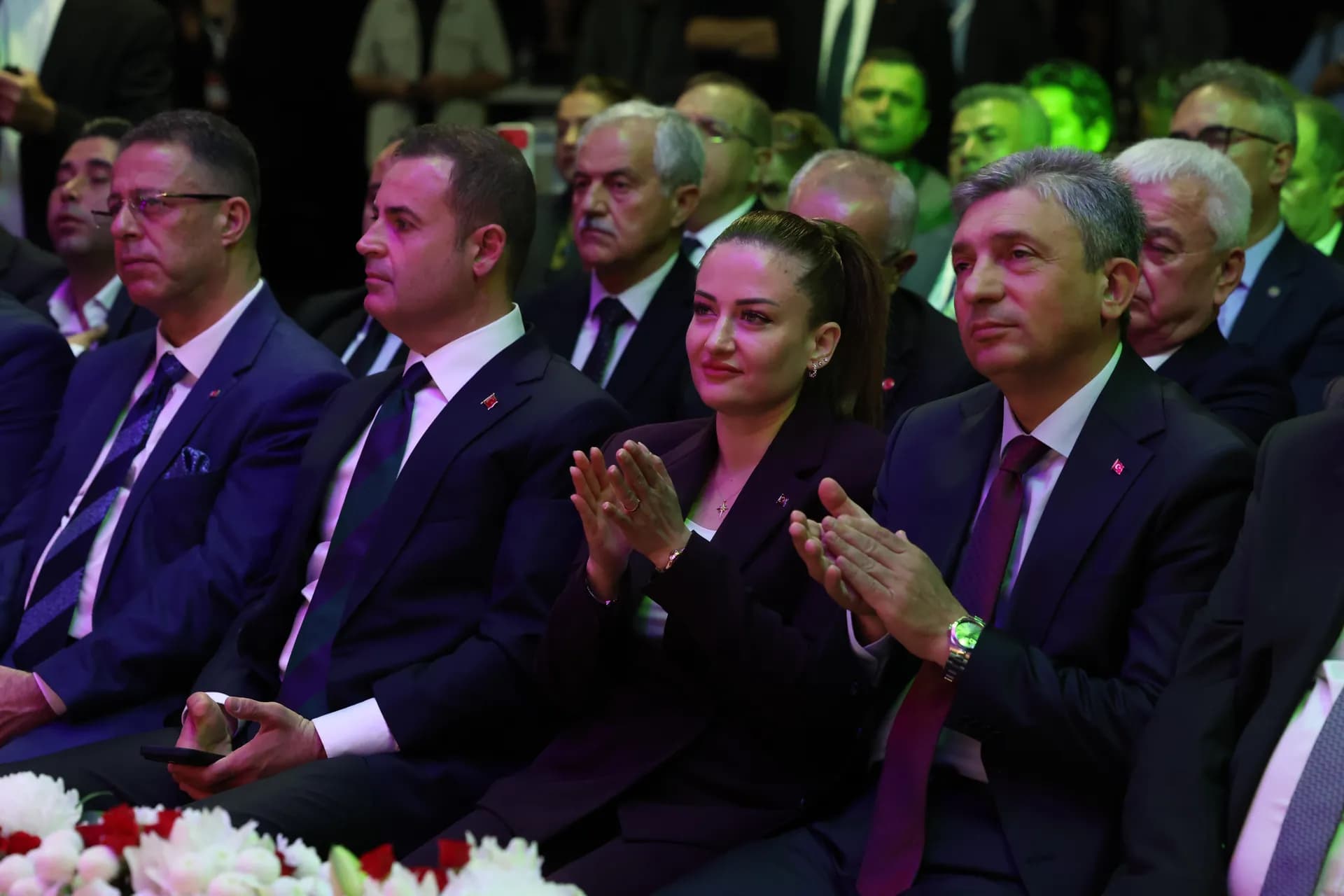 Özdemir yanında Vali Hulusi Şahin ve oturan takım elbiseli erkekler Özdemir ve Şahin alkışlıyorlar