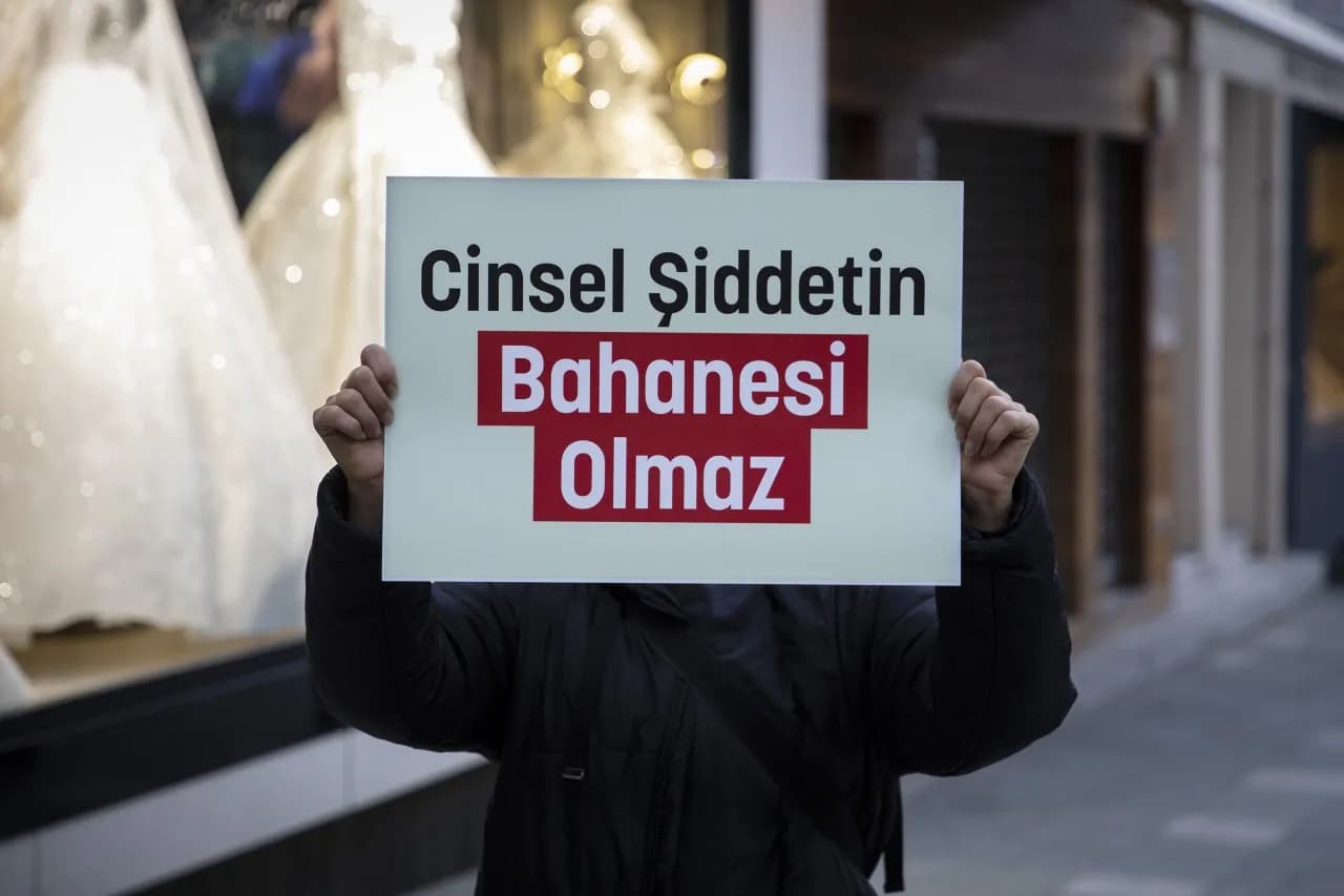 Cinsel şiddetin bahanesi olmaz yazılı afiş birisi tutuyor tutan gözükmüyor 
