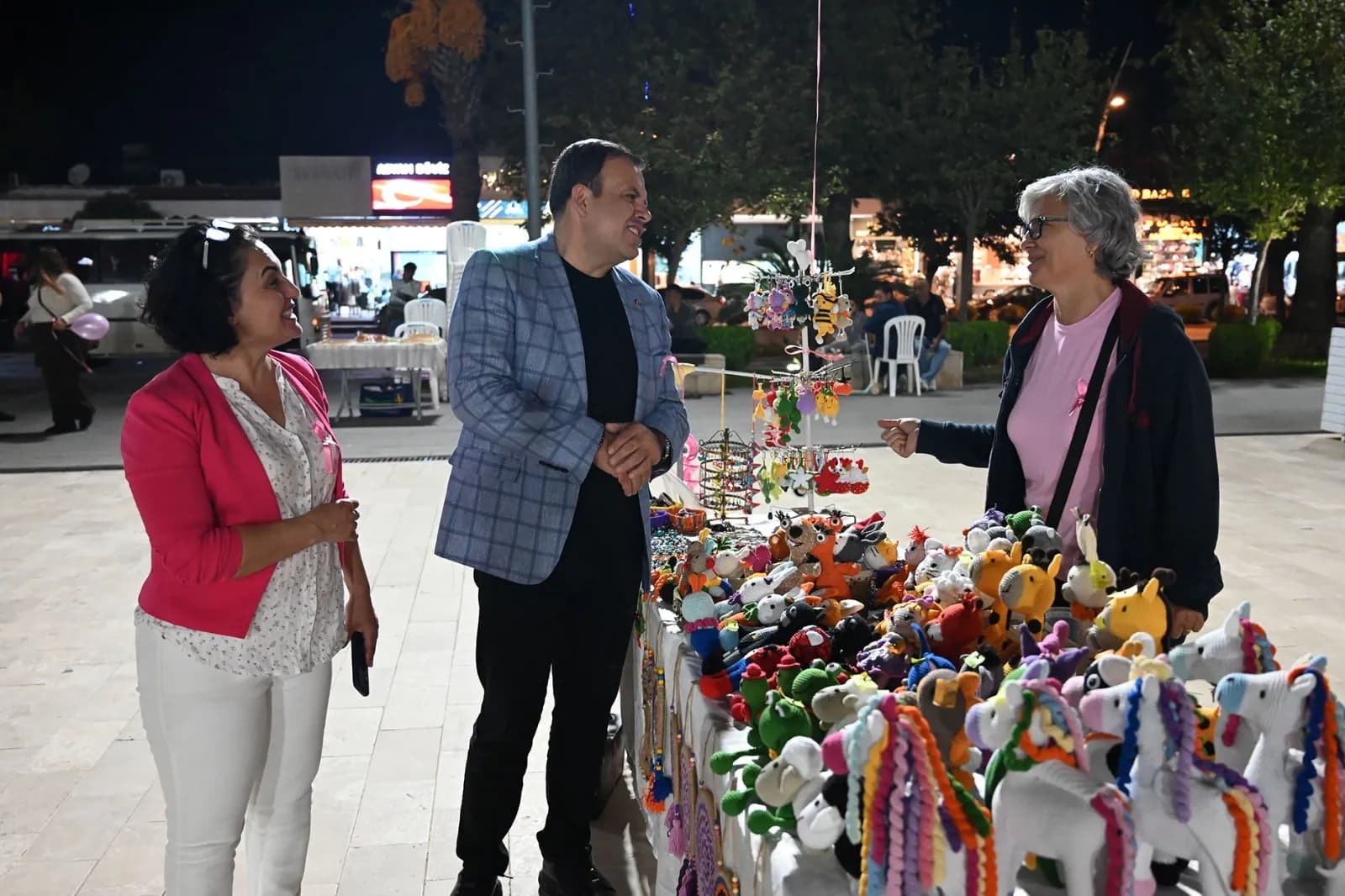 Kermes görüntüsü kermes arkasında kadın bir erkekle konuşuyor erkeğin yanında bir kadın daha var 