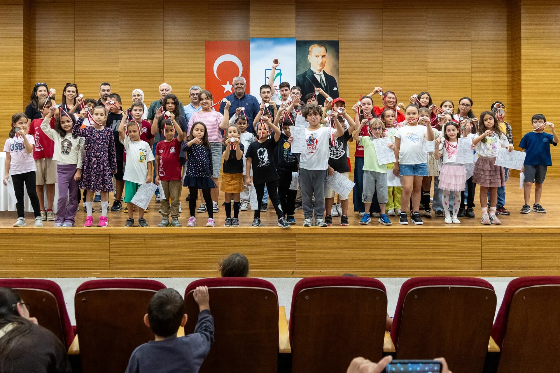 ödül alan çocuklar ellerinde madalyayı tutarak poz veriyor 